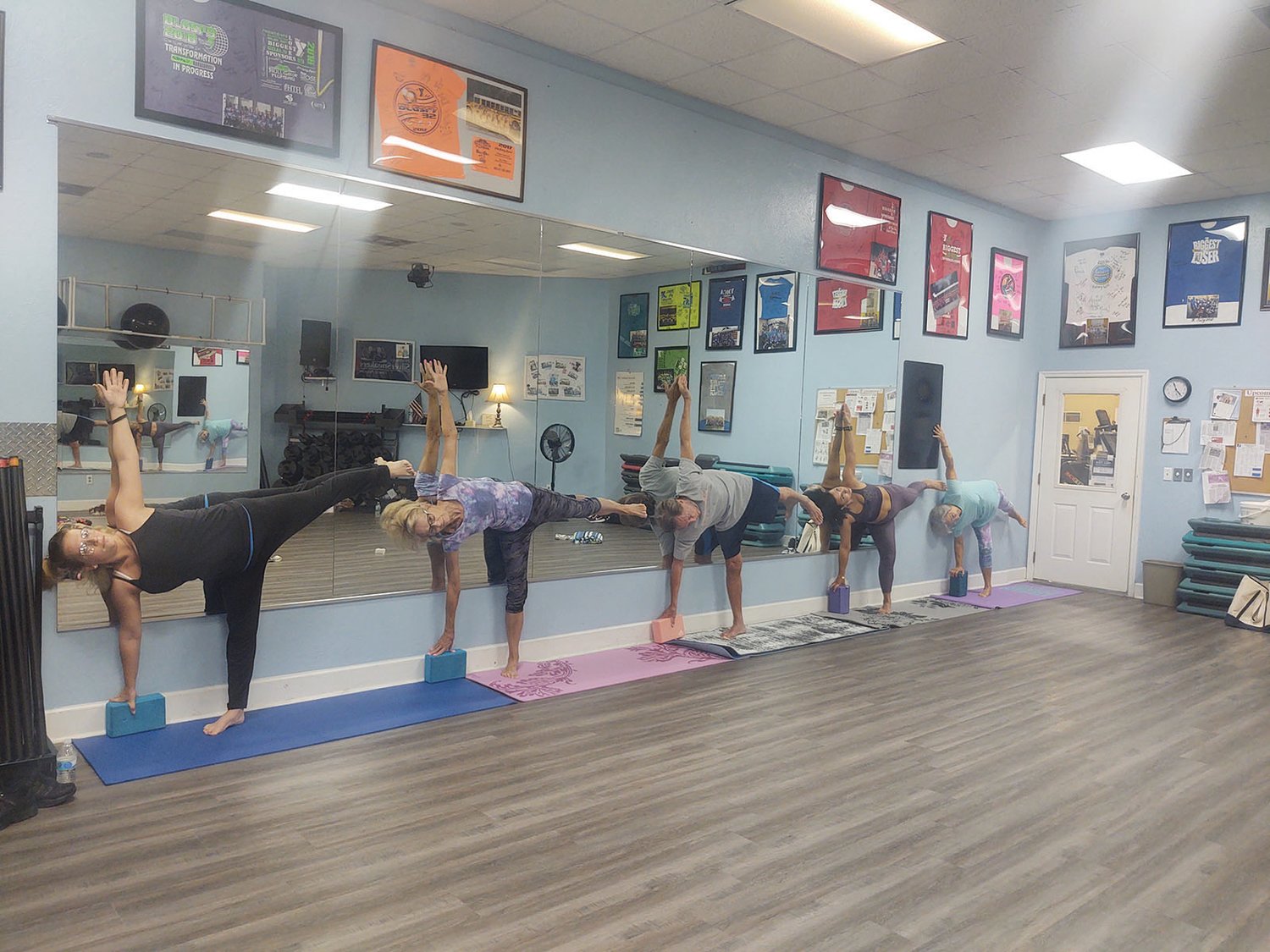 Ashley, Darlene, Ken, Jessica and Linda use blocks and the wall  for stability during a yoga routine.